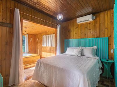 een slaapkamer met een bed in een kamer met houten wanden bij Pousada Canyons do Sul in Praia Grande