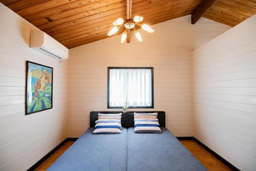 a bed in a room with a ceiling fan at FLEX BEACH HOUSE in Gushiken