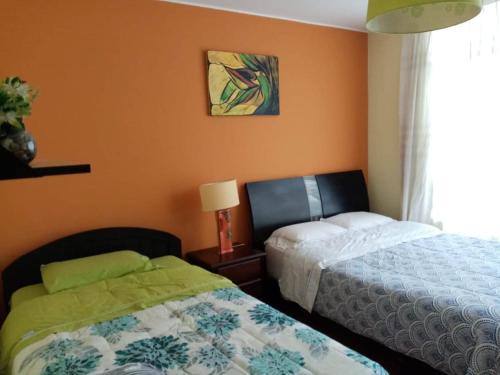 1 dormitorio con 2 camas junto a una ventana en apartamentos Los cedros, en Lima