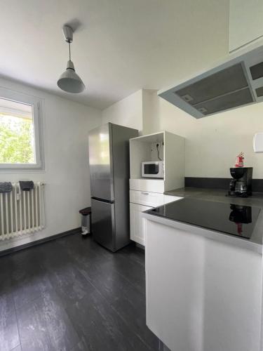 uma cozinha com um frigorífico de aço inoxidável e armários brancos em Appart lumineux au calme 2 ou 3 pers em Chalon-sur-Saône