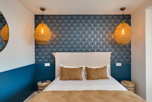a bedroom with a bed with two pillows and two lights at Hôtel & Spa Les Mouettes in Argelès-sur-Mer