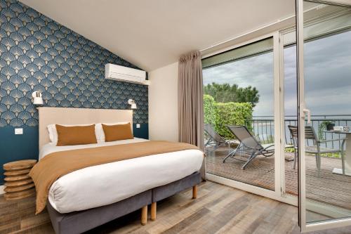 a bedroom with a bed and a balcony at Hôtel & Spa Les Mouettes in Argelès-sur-Mer