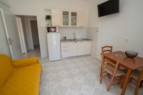 eine Küche mit einem Tisch und eine Küche mit einem Kühlschrank in der Unterkunft Apartments and rooms LJUBICA in Lun