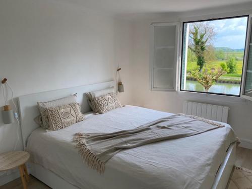 een witte slaapkamer met een bed en een raam bij Le nid des mésanges in Buffon