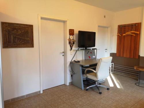 a room with a desk and a chair and a television at Gästewohnung am Pferdehof in Zurndorf