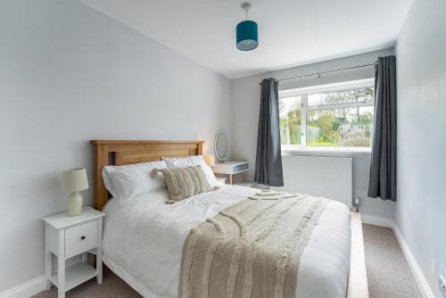 a white bedroom with a bed and a window at Quiet Cotswold Bungalow in Charlbury