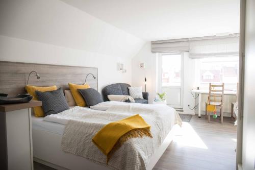 a white bedroom with a large bed with a yellow blanket at Villa Westend in Norderney