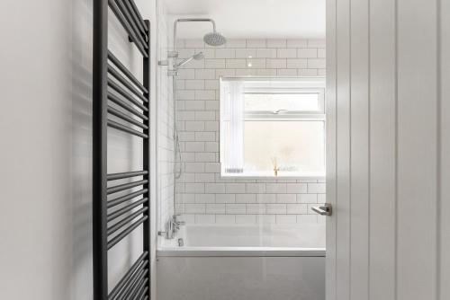 a white bathroom with a tub and a window at Quiet Cotswold Bungalow in Charlbury