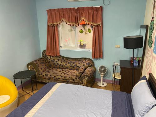 a bedroom with a couch and a bed and a window at Green Island Xinmanyuan綠島馨滿園 in Green Island