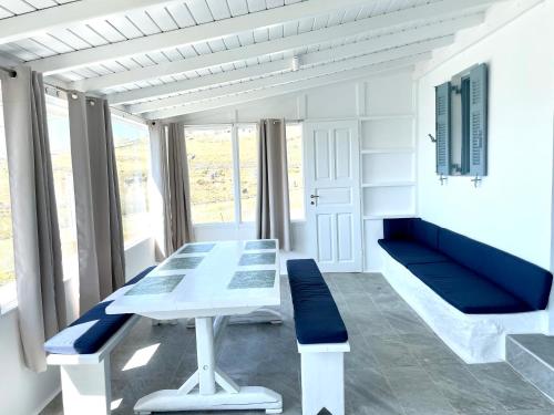 a dining room with a white table and blue benches at Black Pebble Myconian House in Ano Mera