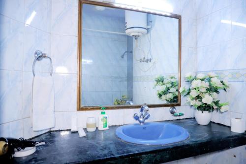 baño con lavabo, espejo y flores en Fortune Home Service Apartment,2Bhk, D-198,SAKET en Nueva Delhi