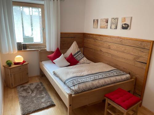 ein kleines Schlafzimmer mit einem Bett mit roten Kissen in der Unterkunft Gästehaus Schneider in Eppishausen