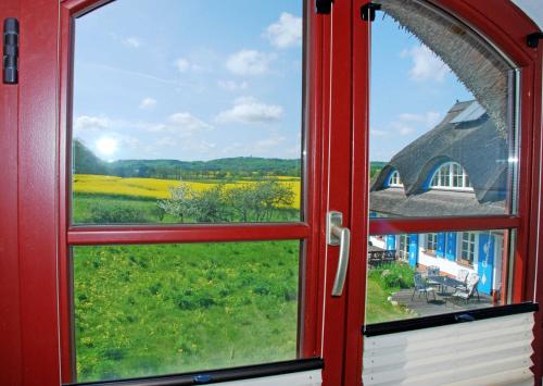 ein offenes Fenster mit Blick auf ein Grasfeld in der Unterkunft Ferienhaus unterm Reetdach in Ostseebad Sellin