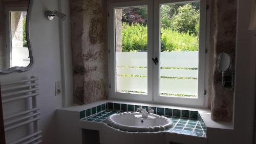 La salle de bains est pourvue d'un lavabo en face d'une fenêtre. dans l'établissement Chambre cocooning, à Malguénac