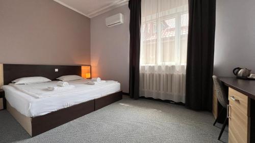 a small bedroom with a bed and a window at TourAsia Hotel in Bishkek