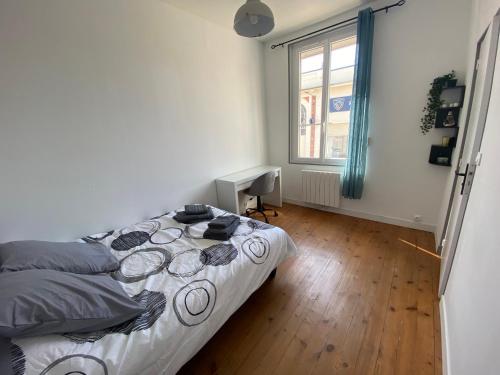 a bedroom with a bed and a desk and a window at Grey Cosy in Louviers
