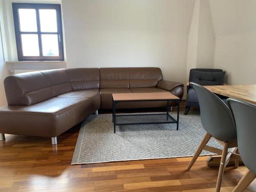 a living room with a brown leather couch and a table at Villa mit Pool und Grillplatz in Regensburg in Regensburg