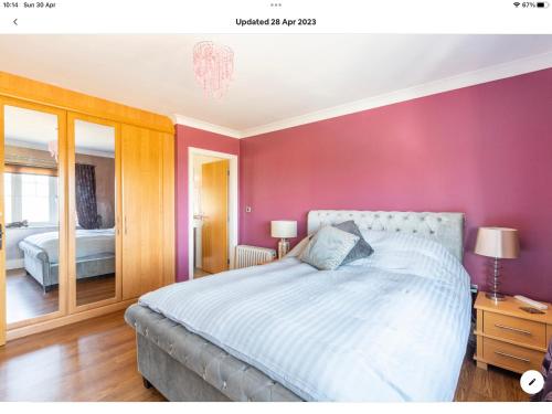 een slaapkamer met een bed en een roze muur bij The Kings Suite Oak Drive, Colwyn Bay LL29 7YP FIRST FLOOR in Colwyn Bay