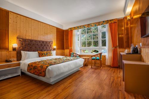 a bedroom with a bed and a desk and a window at Summit Gangchen Hotel in Lachen