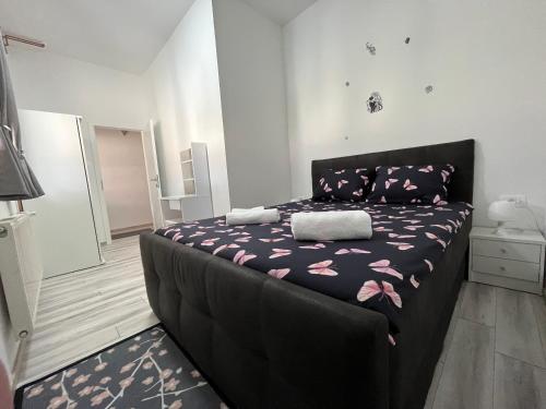 um quarto com uma cama preta e flores cor-de-rosa em Apartment Tilia em Otočac
