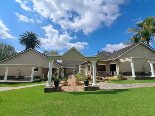 a house with a green lawn in front of it at Longtom Farm Guesthouse in Lydenburg