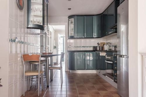 una cocina con armarios verdes y taburetes de bar en Unifamiliar Europa, en Ciudad Real