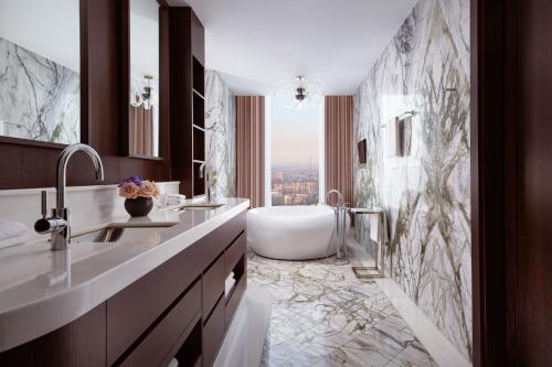a bathroom with a tub and a sink and a bath tub at The Ritz-Carlton, Almaty in Almaty