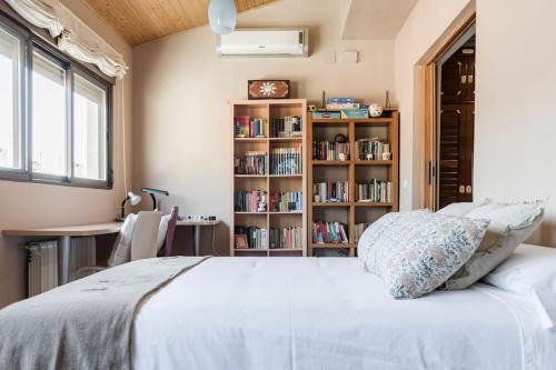 1 dormitorio con cama blanca y estante para libros en Unifamiliar Europa en Ciudad Real