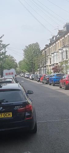 un coche negro conduciendo por una calle con coches aparcados en Stylish London Studio l 1 Bd, 1 Bath Urban Retreat en Londres