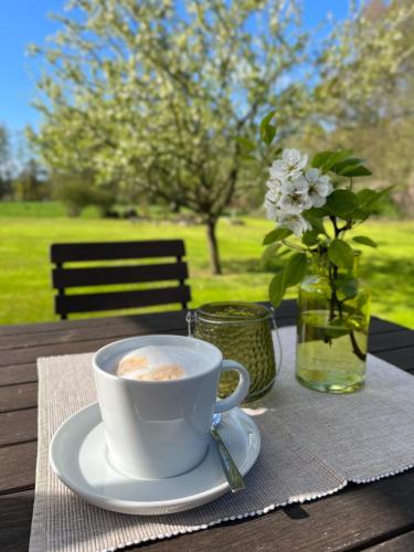 a cup of coffee on a table with a vase of flowers at NaturApartments - Hideaway & Spa in Burg