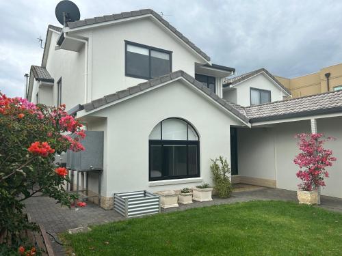 a white house with some flowers in the yard at Kiana Beach House in Port Lincoln
