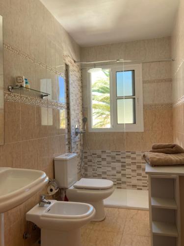a bathroom with a toilet and a sink and a window at Las Rocas Golf and Sea in Caleta De Fuste