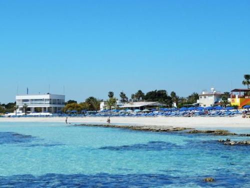 a beach with chairs and people in the water at Tsokkos Paradise Holiday Village in Ayia Napa