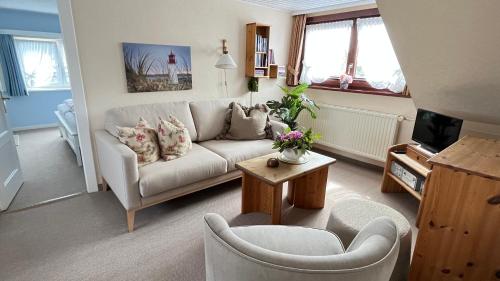ein Wohnzimmer mit einem Sofa und einem Tisch in der Unterkunft Haus Boy Jensen Wohnung Dünenblick in Wenningstedt-Braderup