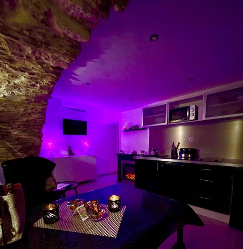 un salon avec éclairage violet et une cuisine dans l'établissement Appartement Love room avec jacuzzi et hammam privatisé Lieu insolite en amoureux Spa détente assurée avec de doux massages en options sur demande, à Orgon