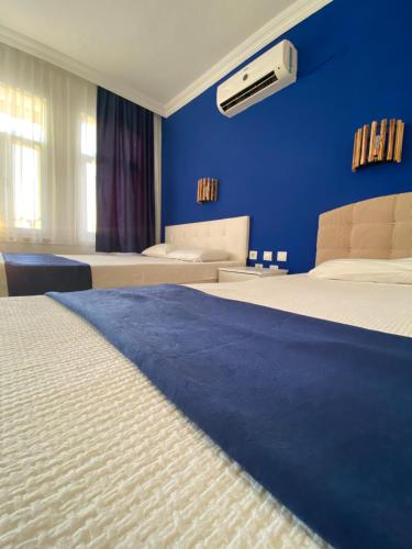 1 dormitorio con 2 camas y pared azul en pH Hotel, en Ölüdeniz