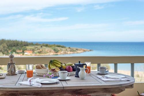 a wooden table with a plate of fruit on a table with the beach at Chryssi Akti Sea View 1 min (100m) from the beach in Daratso
