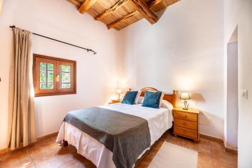 a bedroom with a bed with blue pillows and a window at Villa Can Pep D'en Puig in Sant Mateu d’Albarca
