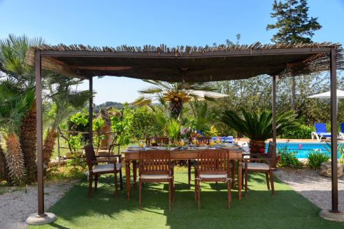 a table and chairs under a pavilion next to a pool at Villa Can Pep D'en Puig in Sant Mateu d’Albarca