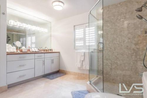 a bathroom with a glass shower and a sink at Delsole- Waterfront Beachhome,heatedpool,wlk2beach in Fort Lauderdale