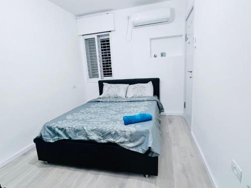 a white bedroom with a bed with a blue tube on it at New! Your home in Israel Luxury Suite in Bat Yam