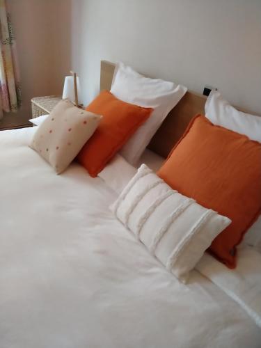 Una cama blanca con almohadas naranjas y blancas. en 'Nulle Part Ailleurs' en Dinant