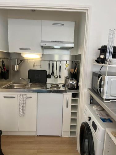 une petite cuisine avec des armoires blanches et un évier dans l'établissement Super Studio centre ville d'Ajaccio, à Ajaccio