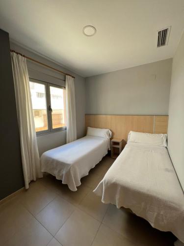 a bedroom with two beds and a window at Hostal Manuela in Punta Umbría