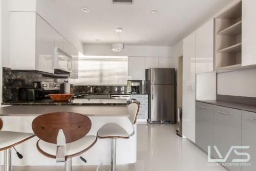 a kitchen with a wooden table and a refrigerator at Delsole- Waterfront Beachhome,heatedpool,wlk2beach in Fort Lauderdale