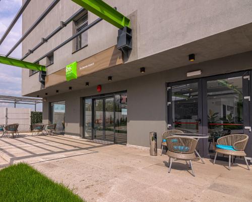 a building with chairs and tables in front of it at Ibis Styles Bucharest Airport in Otopeni