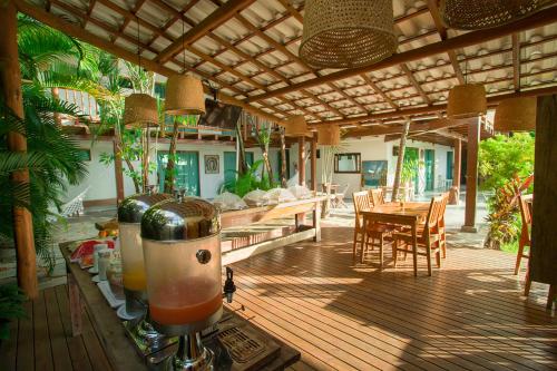 eine Außenterrasse mit einem Tisch, Stühlen und einem Getränk in der Unterkunft Tropical Beach in Porto Seguro