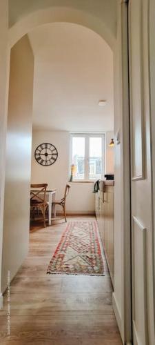 un couloir menant à une cuisine avec une horloge murale dans l'établissement Le Beffroi : appartement cosy en cœur de ville, à Armentières