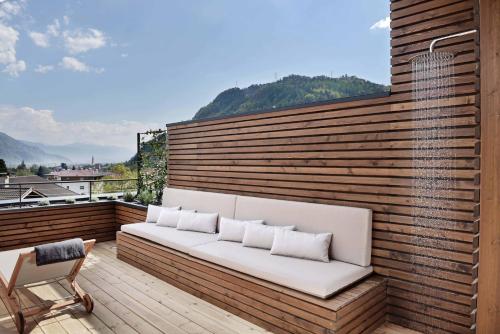 un sofá blanco sentado en una terraza de madera en Hotel Schwarzschmied en Lana