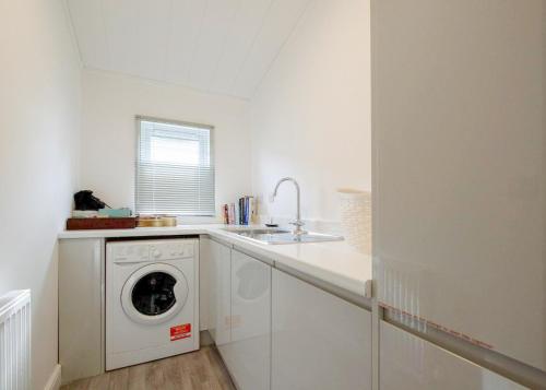 a white kitchen with a washing machine and a sink at Docker Holiday Park in Carnforth